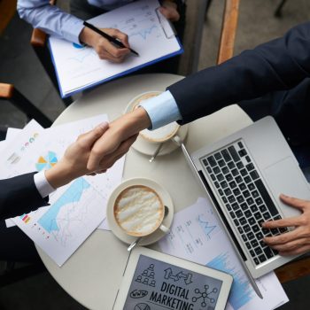 Business people shaking hands overtable with documents